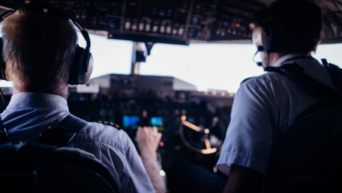 pilots operating airplane in cockpit during flight